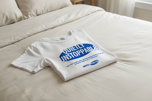 White Quietly Unstoppable t-shirt folded on bed